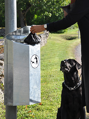 A woman throwing away trash in the Rosen litter bin in galvanized steel.